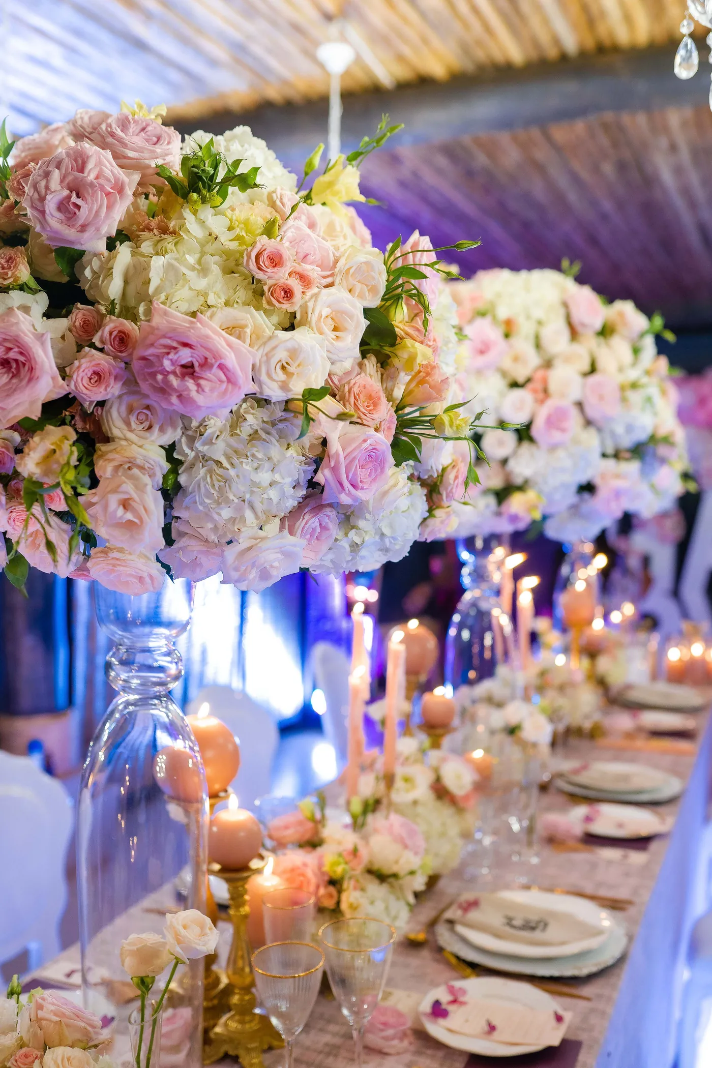 Pink and cream rose centrepieces on a candlelit dining table